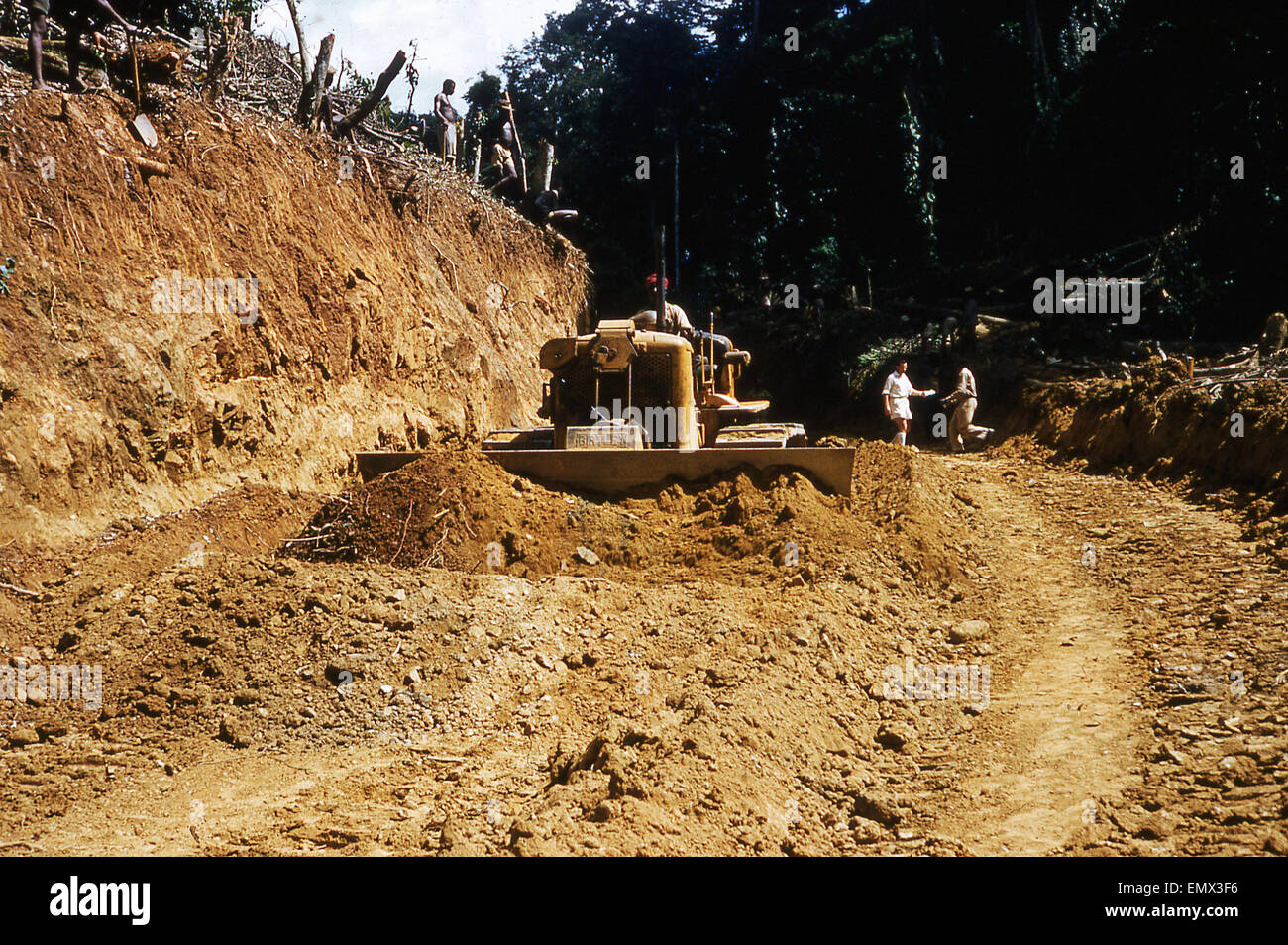 Anni sessanta, storico, Ghana, meccanica del trattore escavatore o effettuare una compensazione attraverso una foresta per il trasporto di legname. Foto Stock