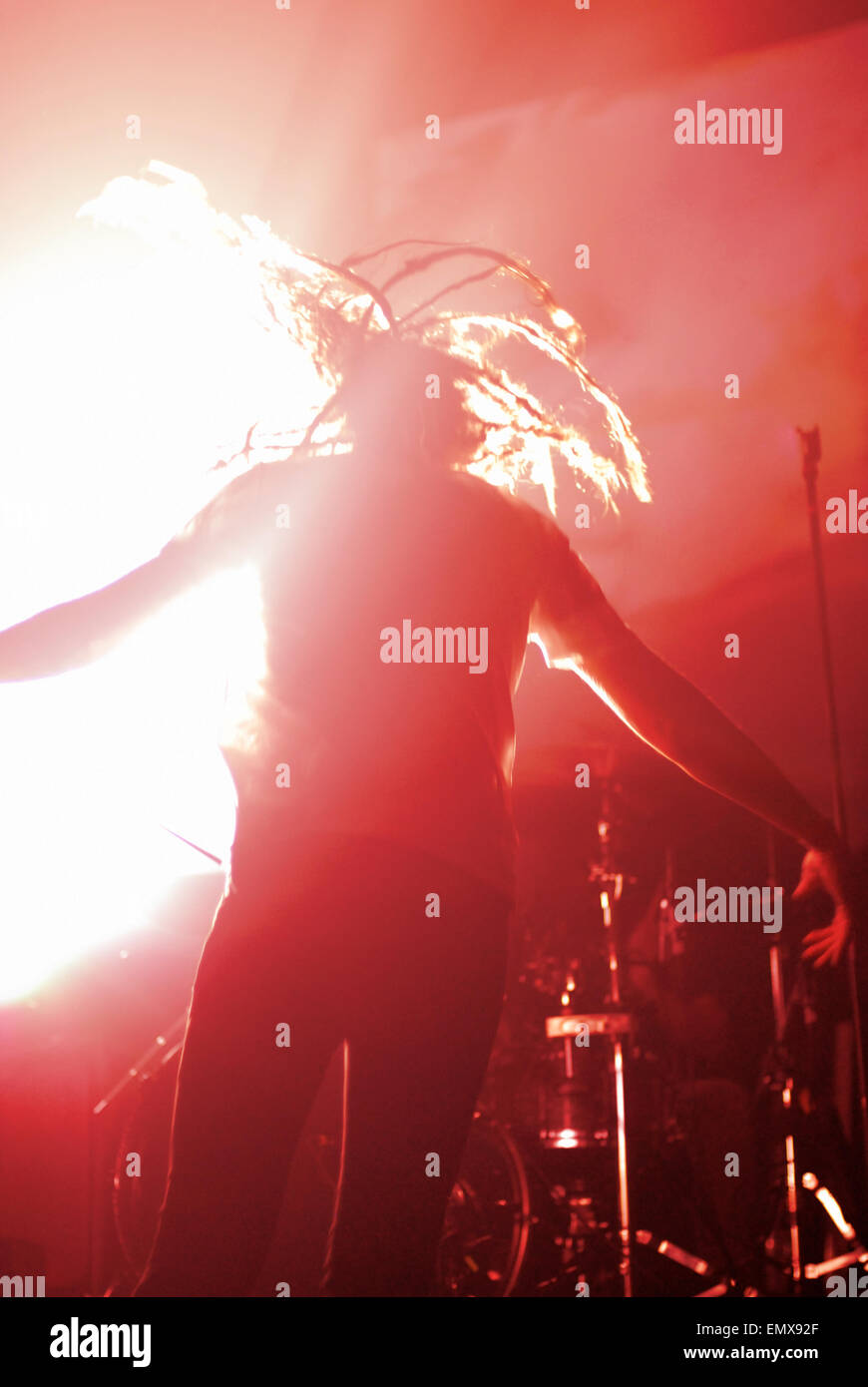 Vista posteriore di un anonimo o anonimi rock star sul palco, saltando e piena di energia, circondato da red illuminazione scenica. Foto Stock
