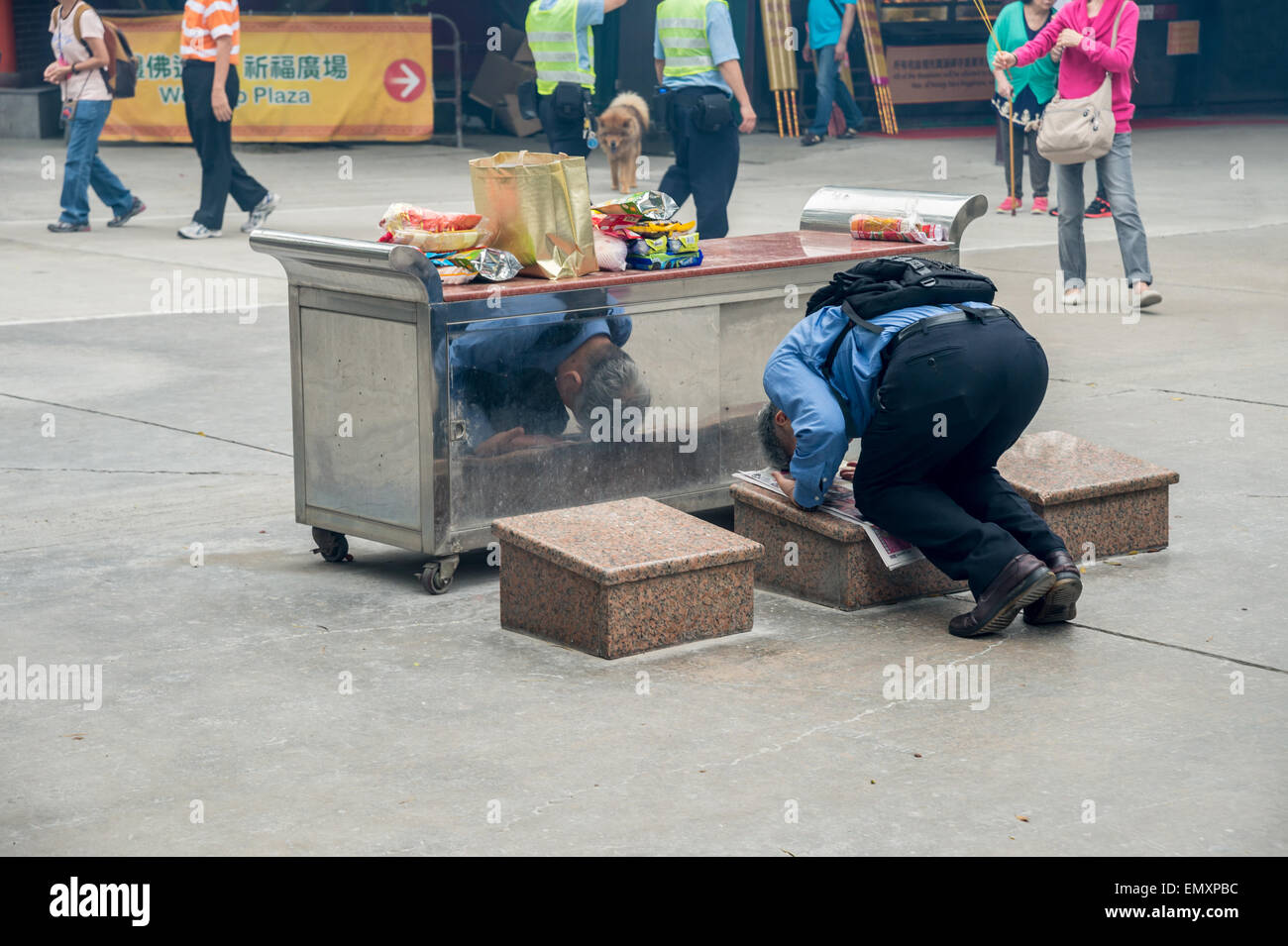 Un uomo che prega e si prostra davanti una tabella di offerte di cibo, al Monastero Po Lin, a Hong Kong, Cina Foto Stock