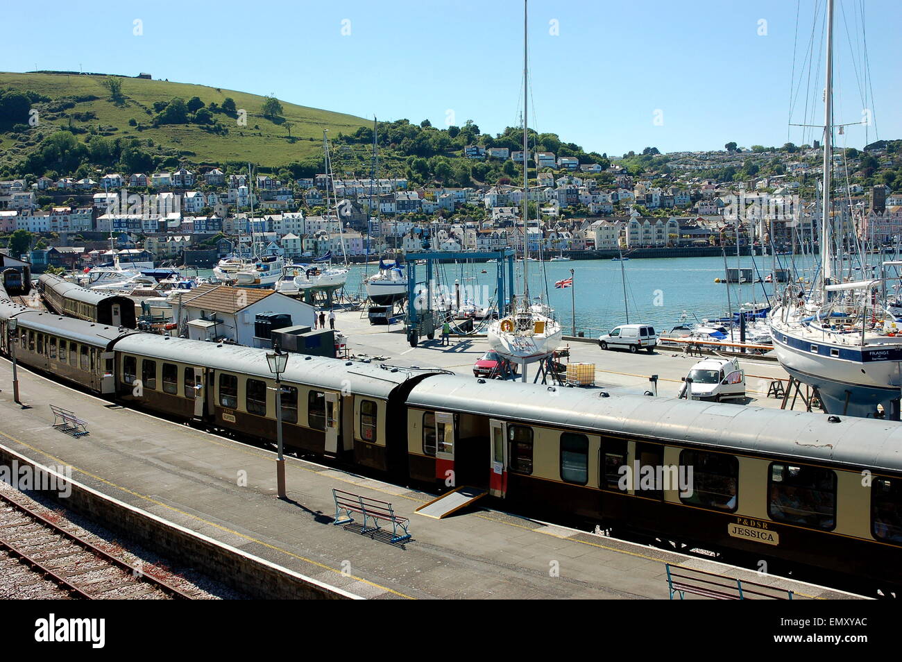 Una vista di un treno in Kingswear stazione ferroviaria. Dietro è il fiume Dart come esso scorre su di Dartmouth e Kingswear. Foto Stock