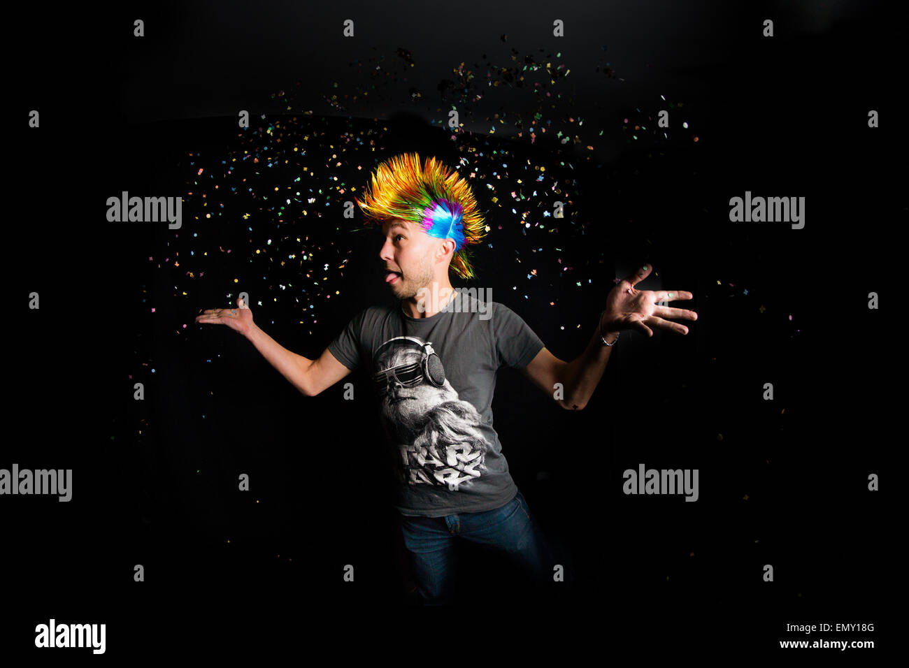 Ritratto di un uomo con capelli colorati gettando coriandoli nell'aria. Foto Stock