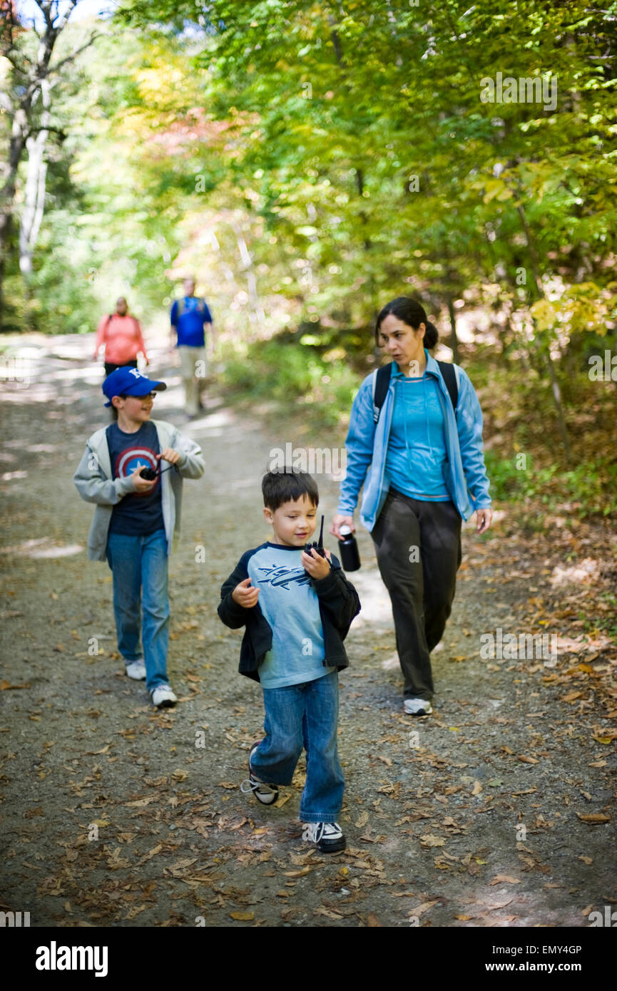 Ispanico madre e bambini (ragazzi di 9 e 5 a piedi attraverso i boschi come giocano con i loro walkie talkie. Foto Stock