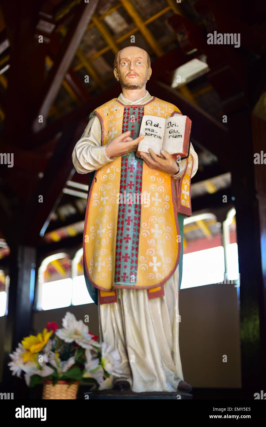 Statua di Sant'Ignazio di Loyola che mostra un libro con la frase latina scritta all'interno, alla chiesa di Sant'Ignazio Loyola a Sikka, Isola di Flores, Indonesia. Foto Stock