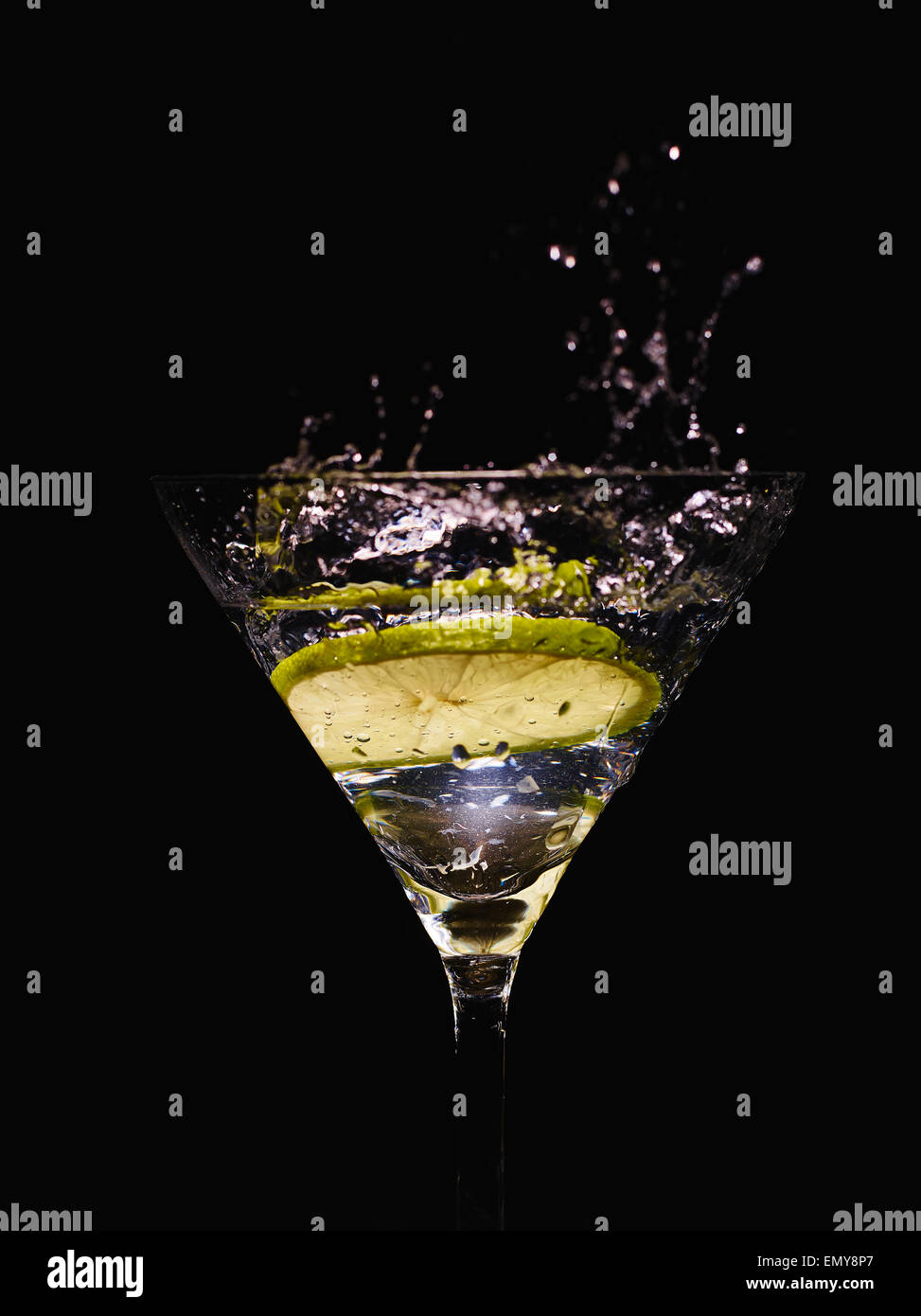 Coppetta Martini e bevande alcoliche con una fetta di lime, schizzi, sfondo nero Foto Stock