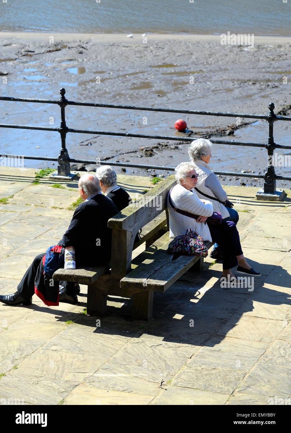 I pensionati seduti sui banchi a Whitby fronte mare,North Yorkshire, Inghilterra, Regno Unito Foto Stock
