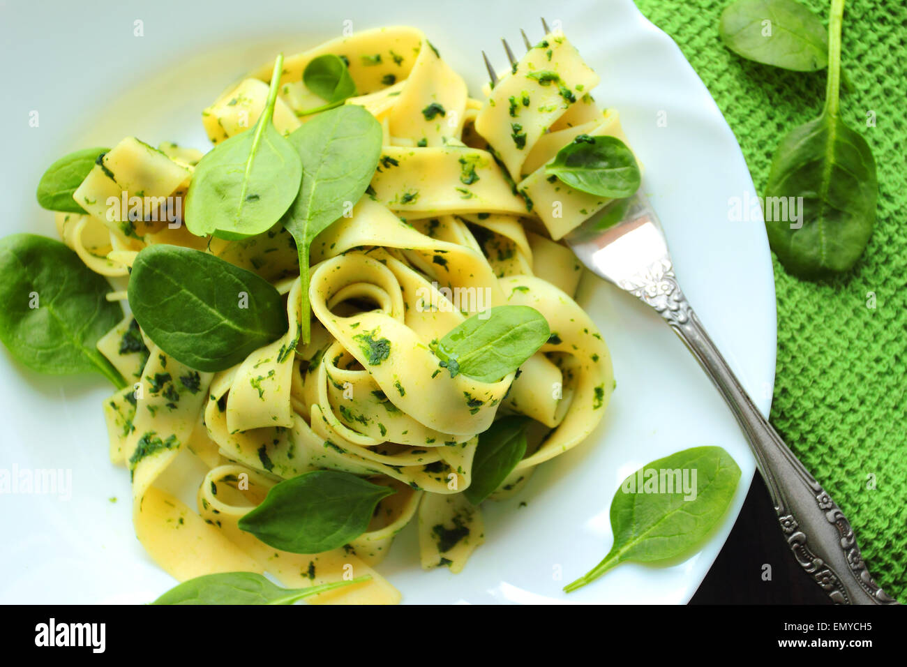Tagliatelle con salsa di spinaci freschi e foglie su una piastra bianca Foto Stock