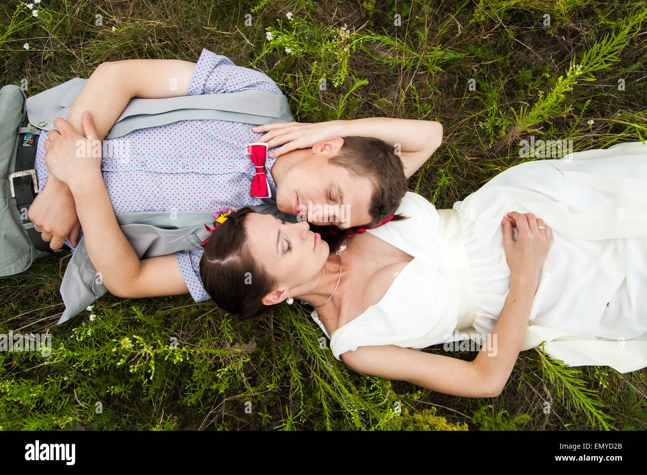 Coppie in viaggio di nozze in amore giacente in verde erba di prato estivo. Felice sposa e lo sposo rilassante al di fuori Foto Stock
