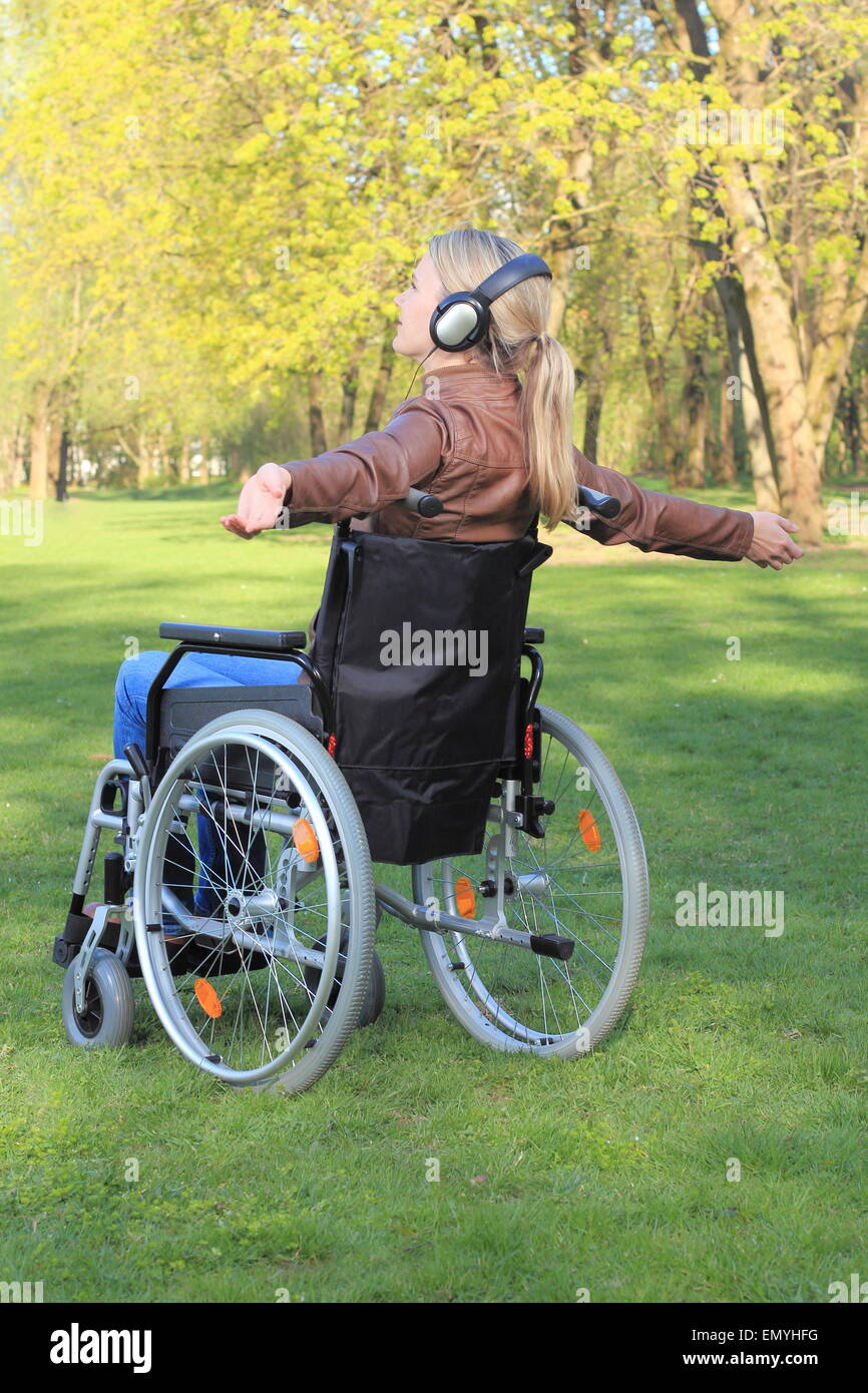 Una donna felice in una sedia a rotelle con le braccia distese Foto Stock