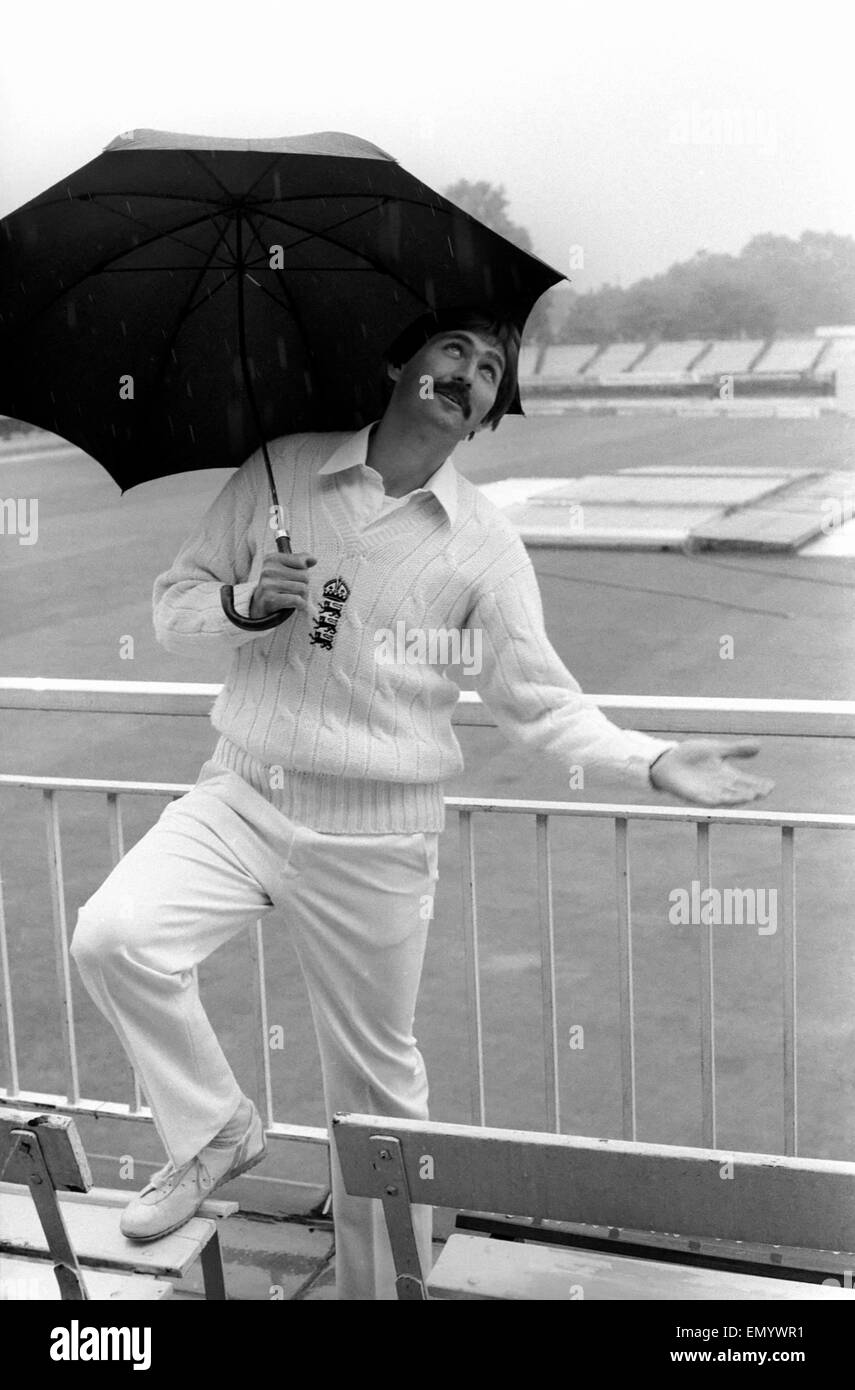 Graham Gooch Inghilterra cricketer prende riparo dalla pioggia sotto un ombrello. Foto Stock