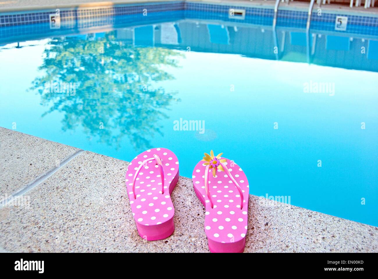 Rosa chiaro e bianco polka flip-flop dal bordo della piscina. Foto Stock