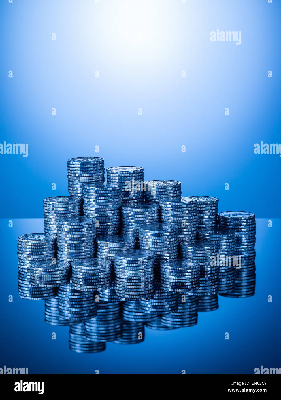 Cataste o pile di monete svizzere, due pezzi di franchi con la riflessione sulla superficie lucida, blu gradiente dello sfondo, formato verticale Foto Stock
