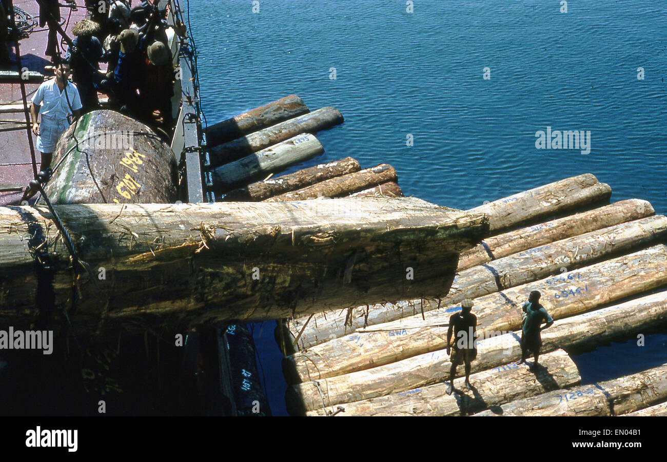 Anni sessanta, Ghana, grandi tronchi o legname viene caricato dall'acqua al di sotto, e su uno scafo di nave per esportazione in Takoradi Porto. Foto Stock