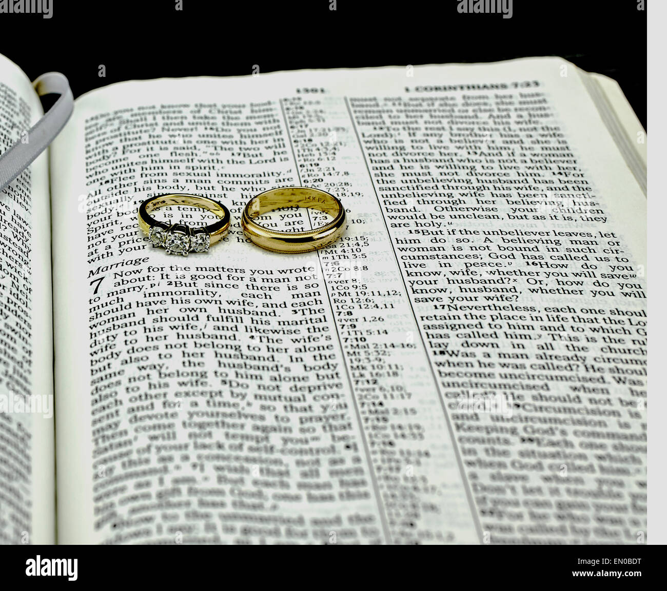 Primo piano della Bibbia generico rivolto al passaggio sul matrimonio con diamanti e oro anelli di nozze su sfondo nero. Foto Stock