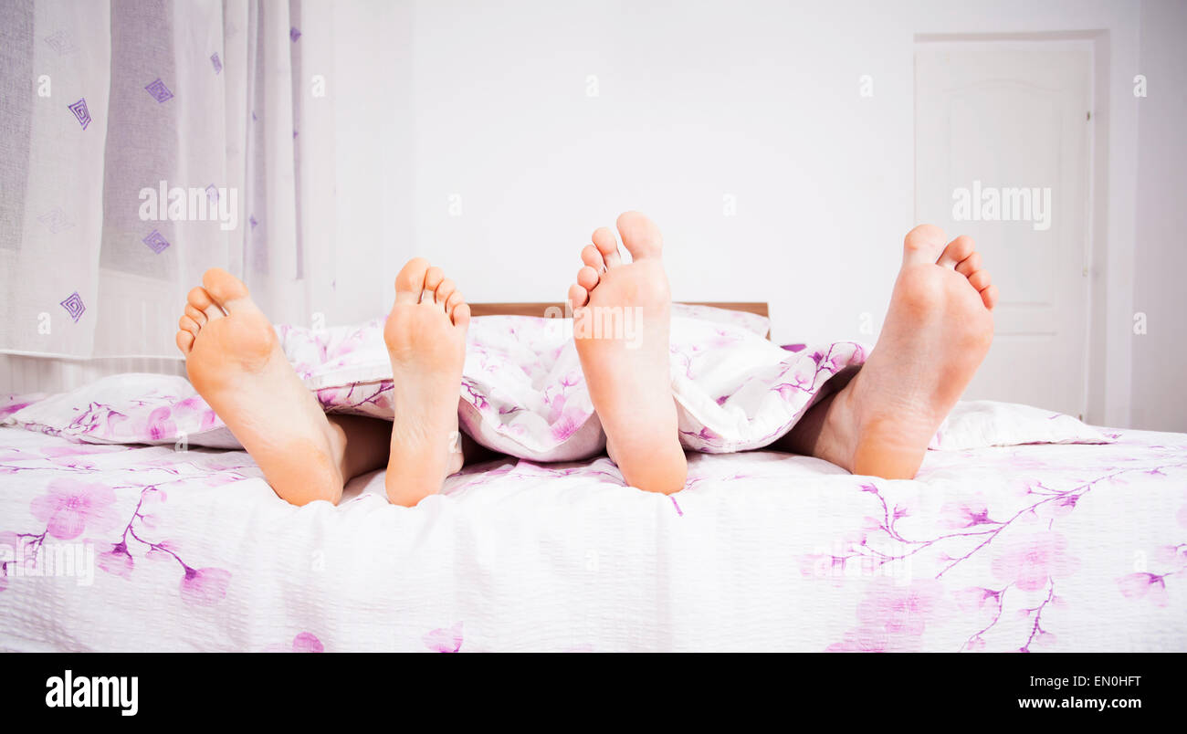 I piedi di un giovane dormendo fianco a fianco nel letto matrimoniale Foto Stock