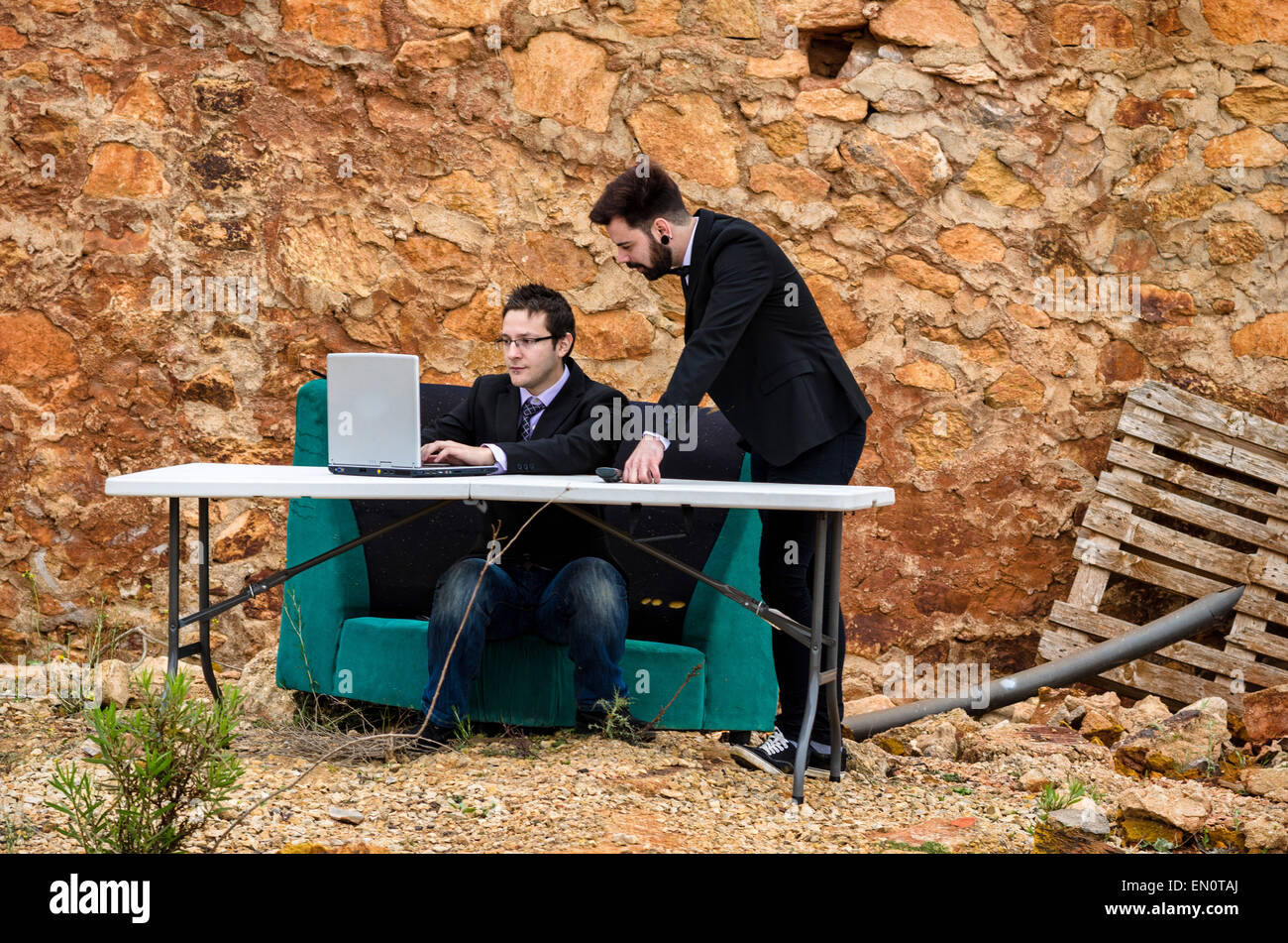 Due ragazzi intorno ad una scrivania in un ufficio di grunge, un concetto di fallimento Foto Stock