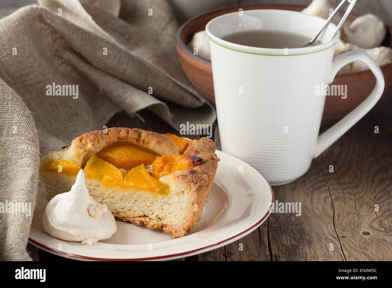 Pasta frolla torta di pesche, meringa e tazza di tè il fuoco selettivo in orizzontale Foto Stock