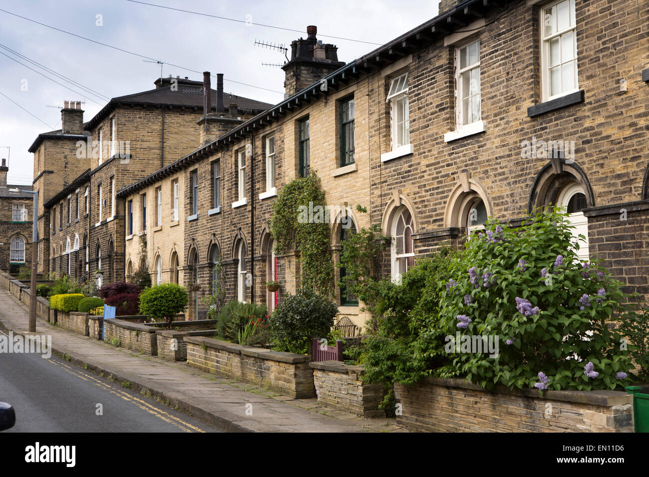 Regno Unito, Inghilterra, Yorkshire, Saltaire, Henry Street terrazza di case con piccoli giardini anteriore Foto Stock