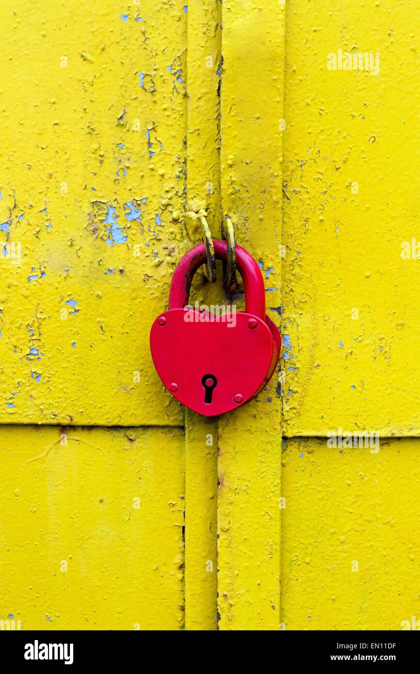 Il dispositivo di bloccaggio rosso su un arrugginito gialla porta Foto Stock