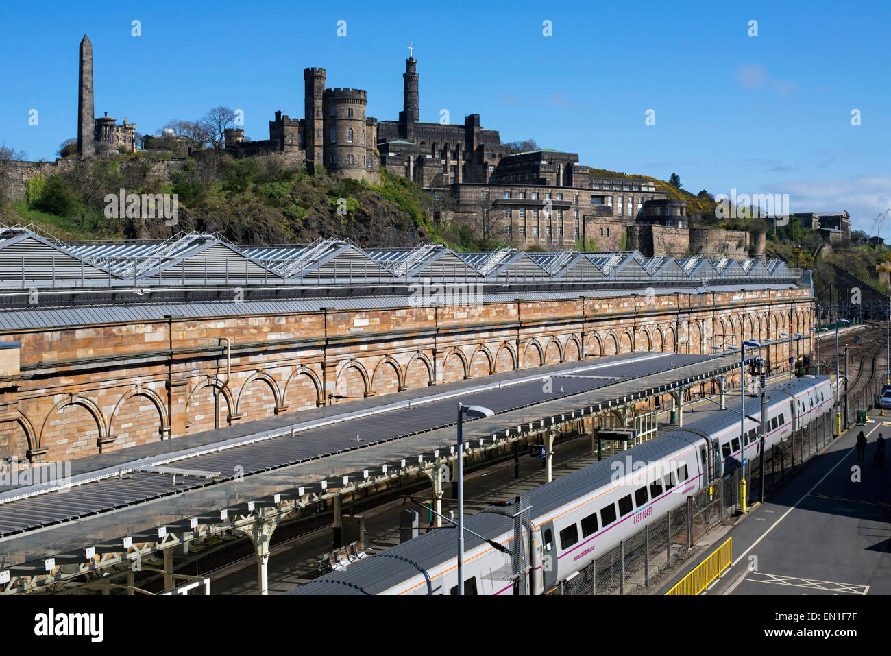 Un East Coast stazione permanente al Edinburgh Waverley Station con Calton Hill in background. Foto Stock
