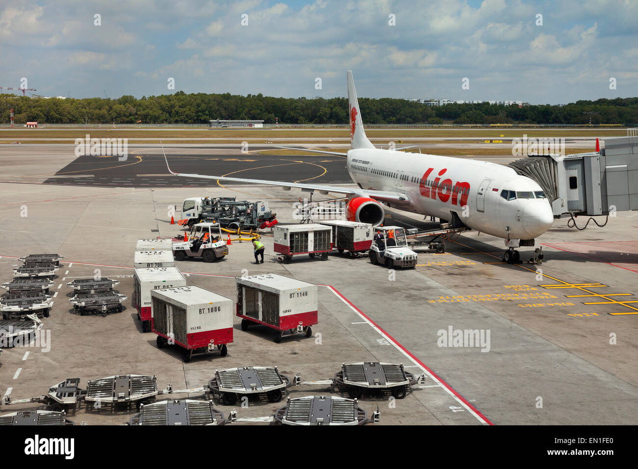 Boeing 737-900ER lato aria aeroporto, la manutenzione e il personale di carico bagagli dei passeggeri in un piano di attesa tramite un nastro trasportatore Foto Stock
