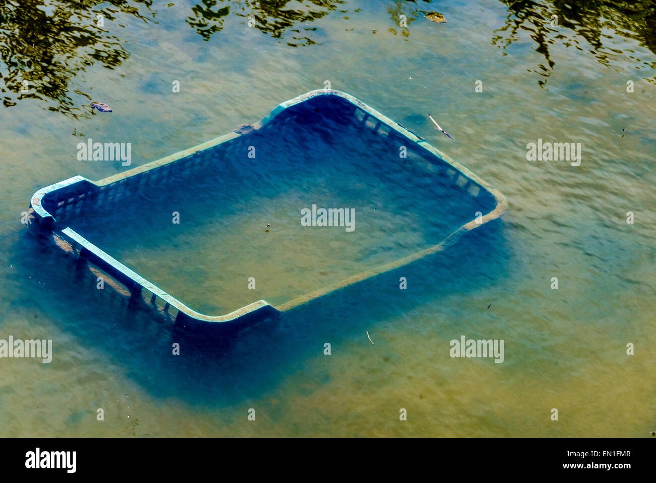 Scatole di plastica tirato in un fiume con acqua contaminata Foto Stock