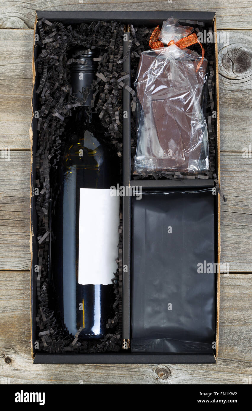 L'immagine verticale di una confezione regalo con il vino, cioccolato e un sacco di caffè sulla parte superiore di legno rustico. Foto Stock