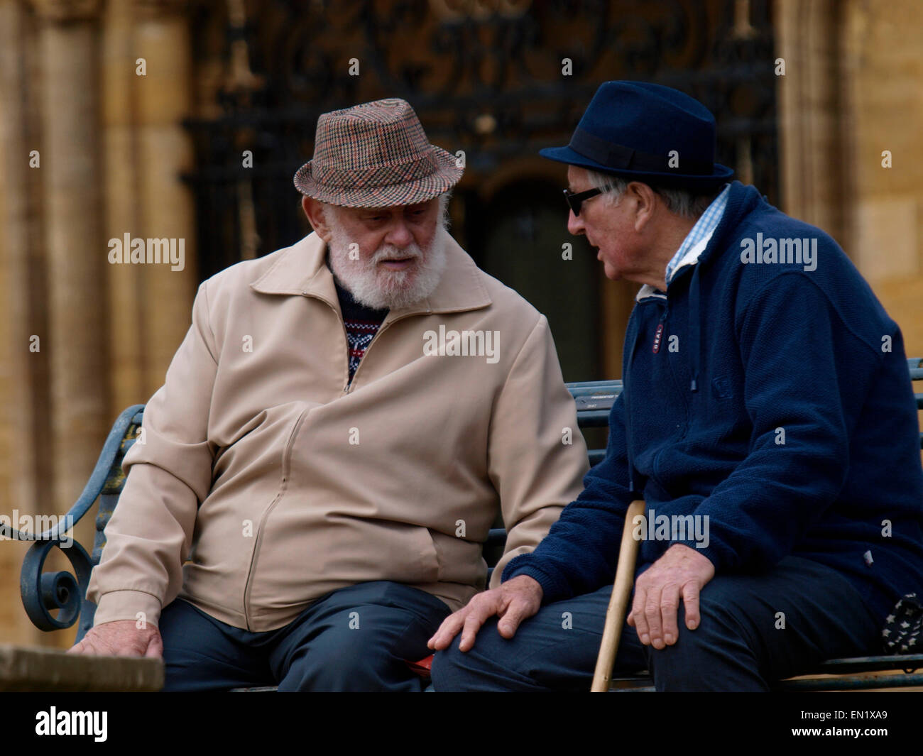 Due uomini anziani seduto su una panchina pubblica chat, Sherborne, Regno Unito Foto Stock