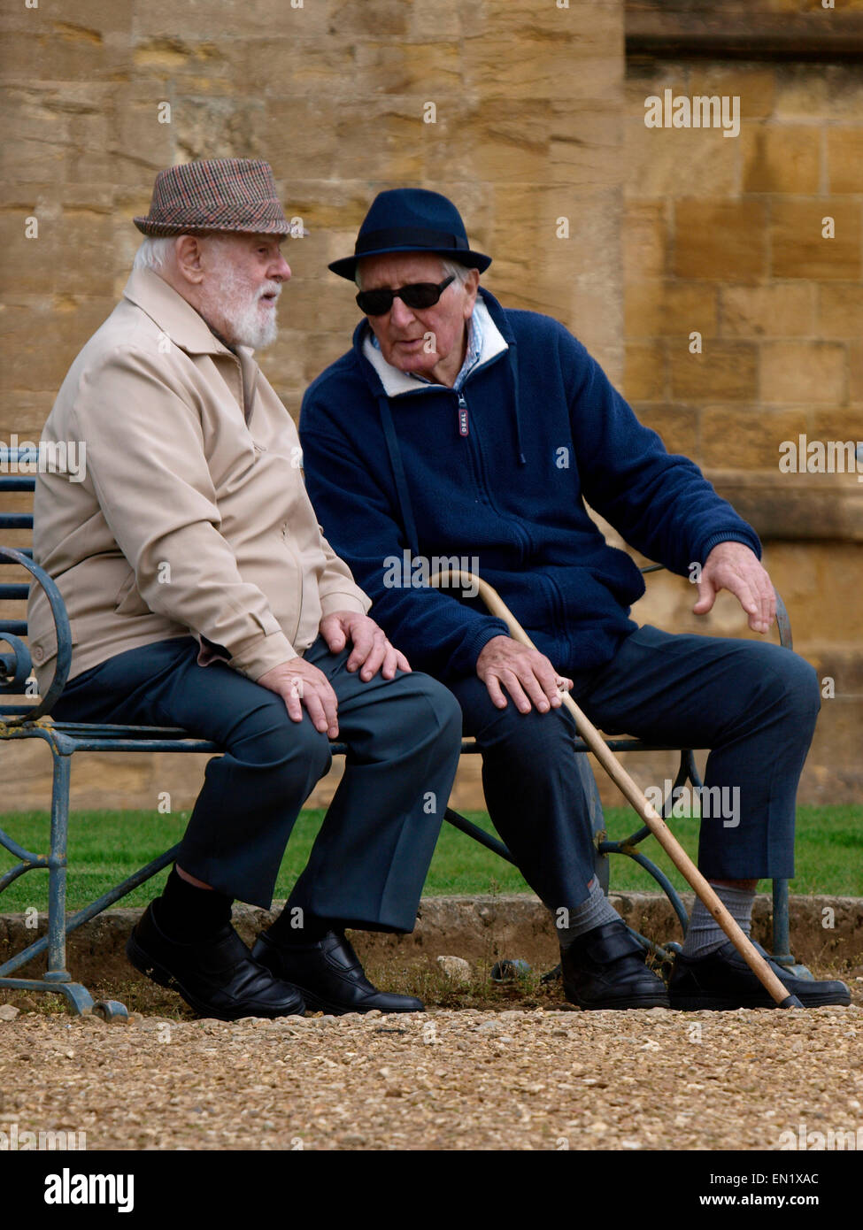 Due uomini anziani seduto su una panchina pubblica, Sherborne, Regno Unito Foto Stock