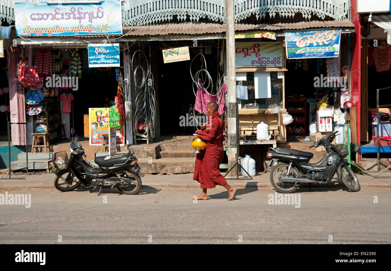 Monaco buddista camminare davanti a un negozio di fronte e ciclomotori a Maymyo Myanmar Foto Stock