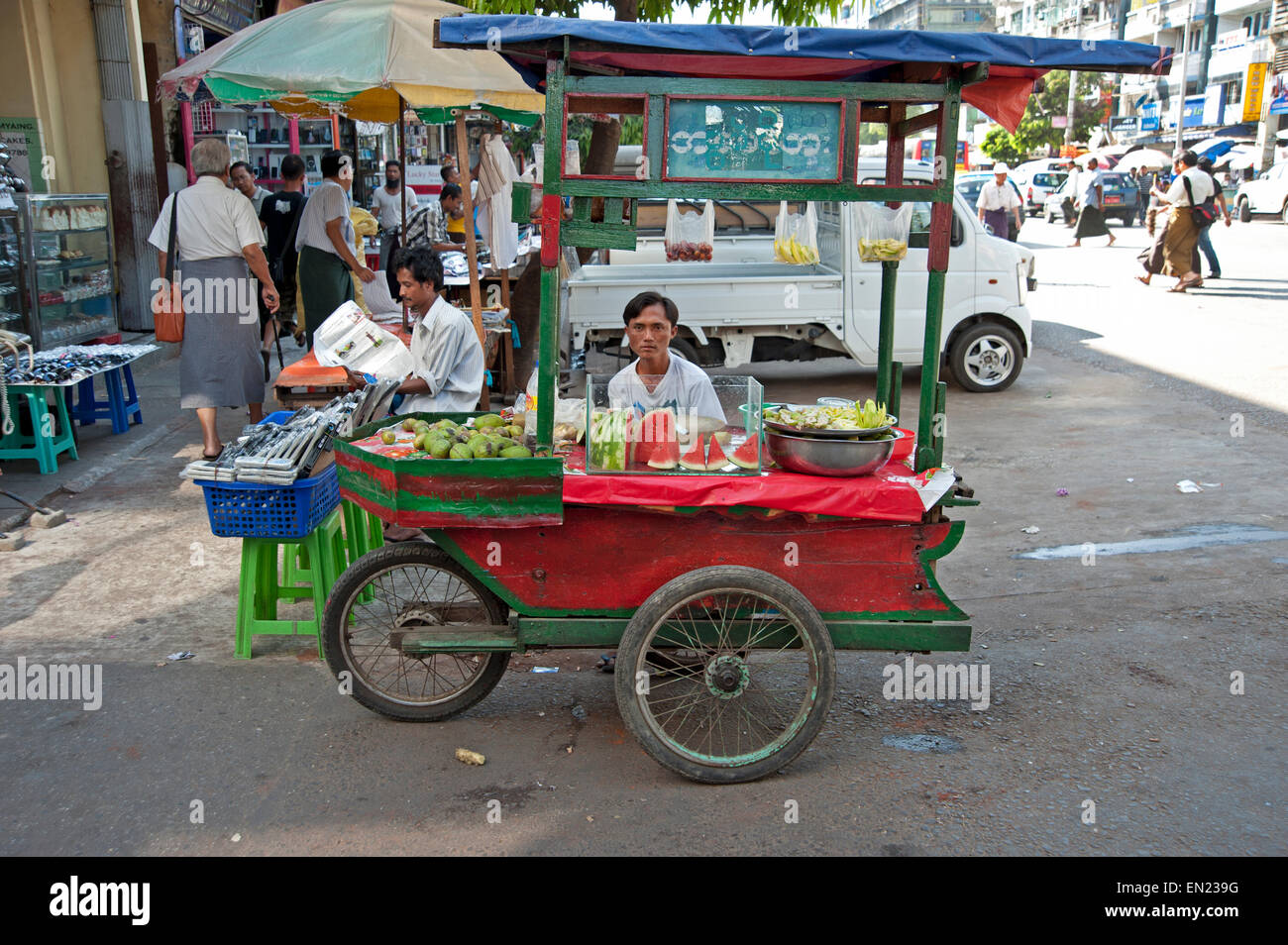 Un uomo si siede dietro il suo cocomero frutta mobile stallo stallo in Yangon Myanmar Foto Stock