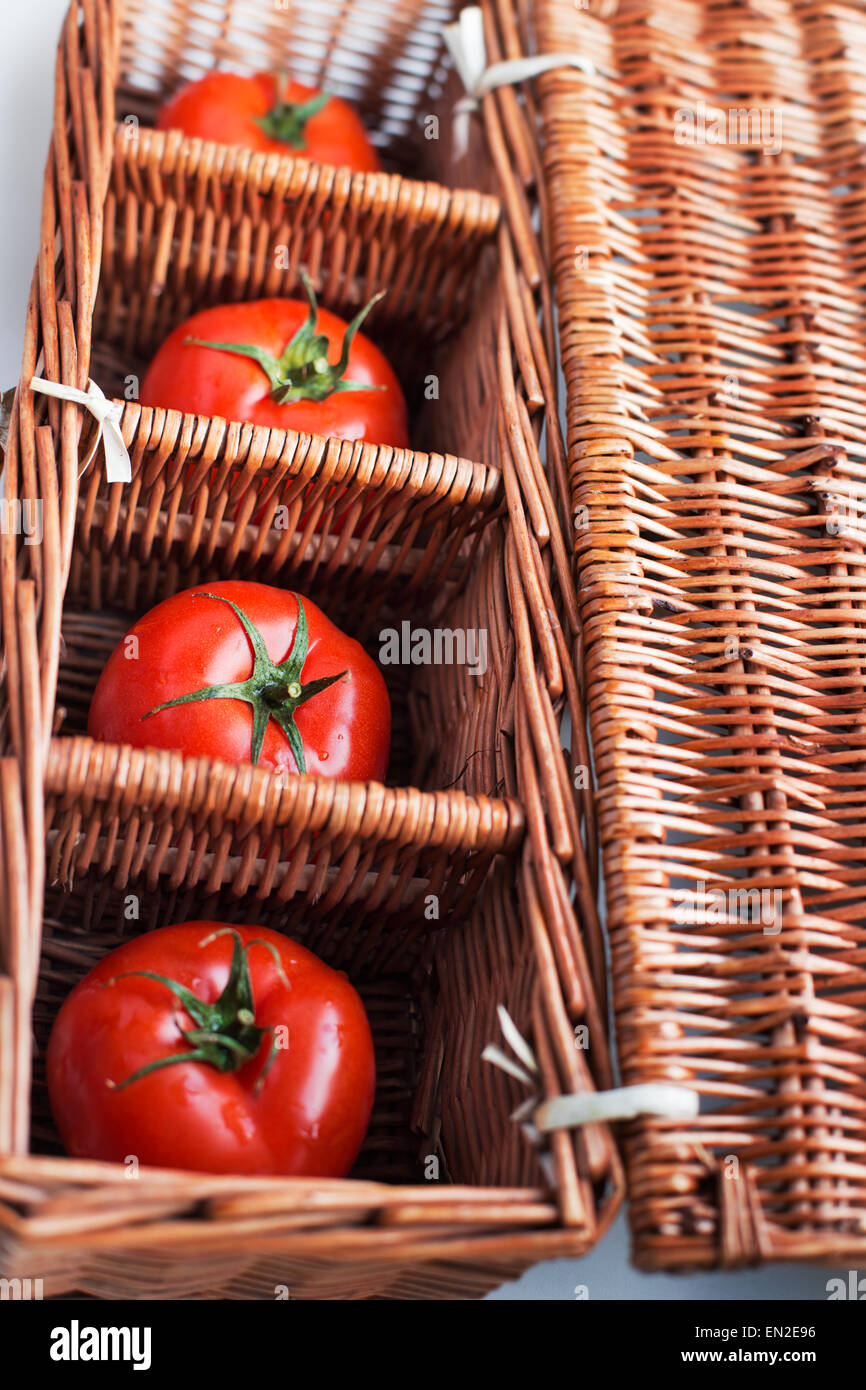 Quattro pomodori giacente separatamente nella casella di vimini Foto Stock