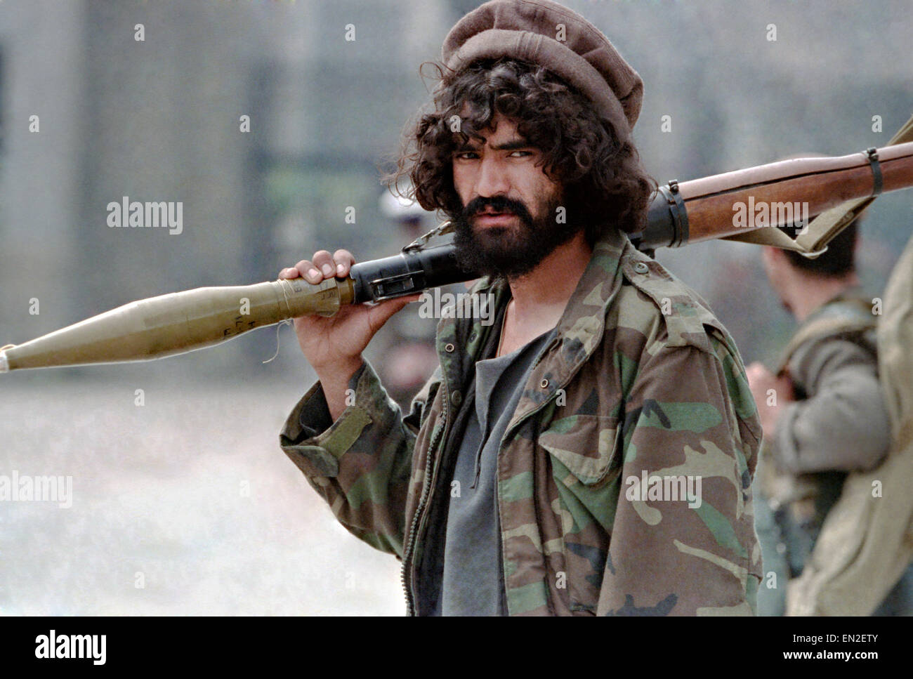 Un Afghan mujahideen fighter con Jamayat-e-Islami trasporta una spalla cotta lanciarazzi granata durante la lotta contro Hezb-i Islami forze dopo la caduta della capitale Aprile 19, 1992 a Kabul, Afghanistan. Combattimenti tra fazioni mujahideen cominciò quasi immediatamente dopo aver catturato la città. Foto Stock