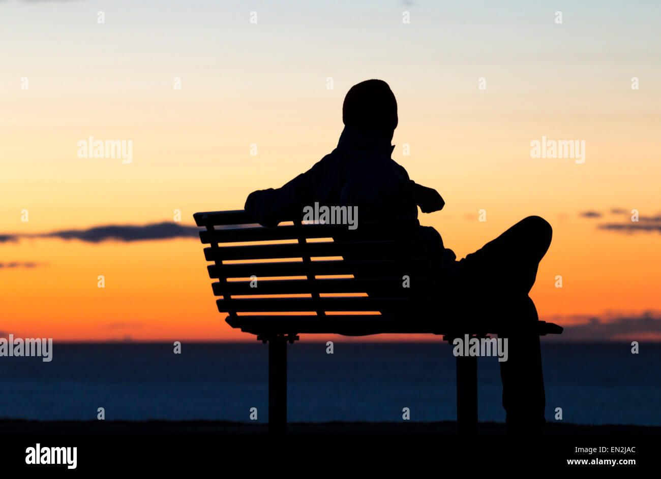 Depressione, solitudine... concetto di immagine. Silhouette di uomo seduto  da solo sul sedile affacciato sul mare al tramonto Foto stock - Alamy