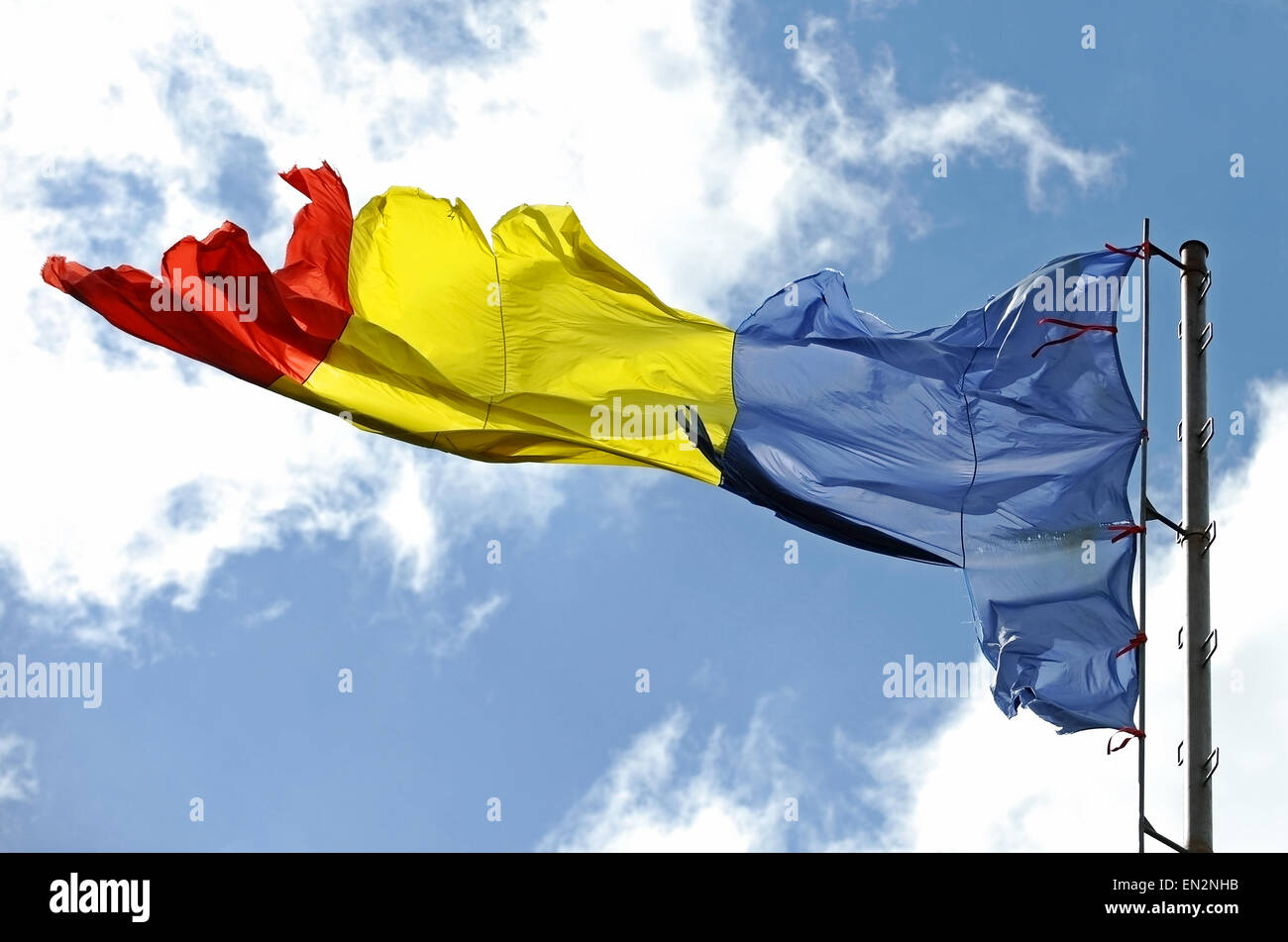Bandiera rumena di strappati dal vento con cielo blu su sfondo Foto Stock