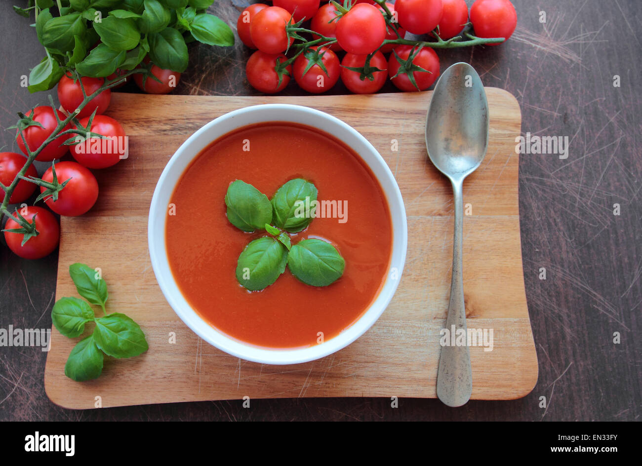 Ciotola con crema di pomodoro zuppa su pannello di legno Foto Stock