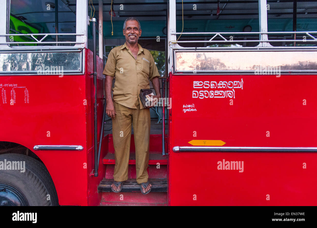 Autista di autobus di fronte ad un bus rosso, Kerala, India Foto Stock