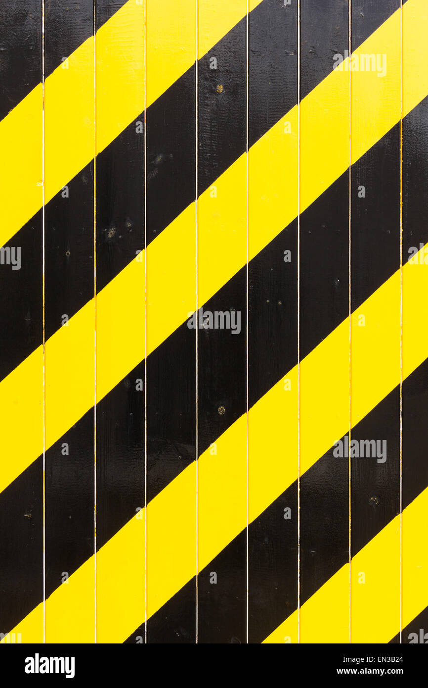 Telaio completo nero e giallo brillante diagonale strisce di avvertimento dipinta su un industriale porta di legno. Foto Stock