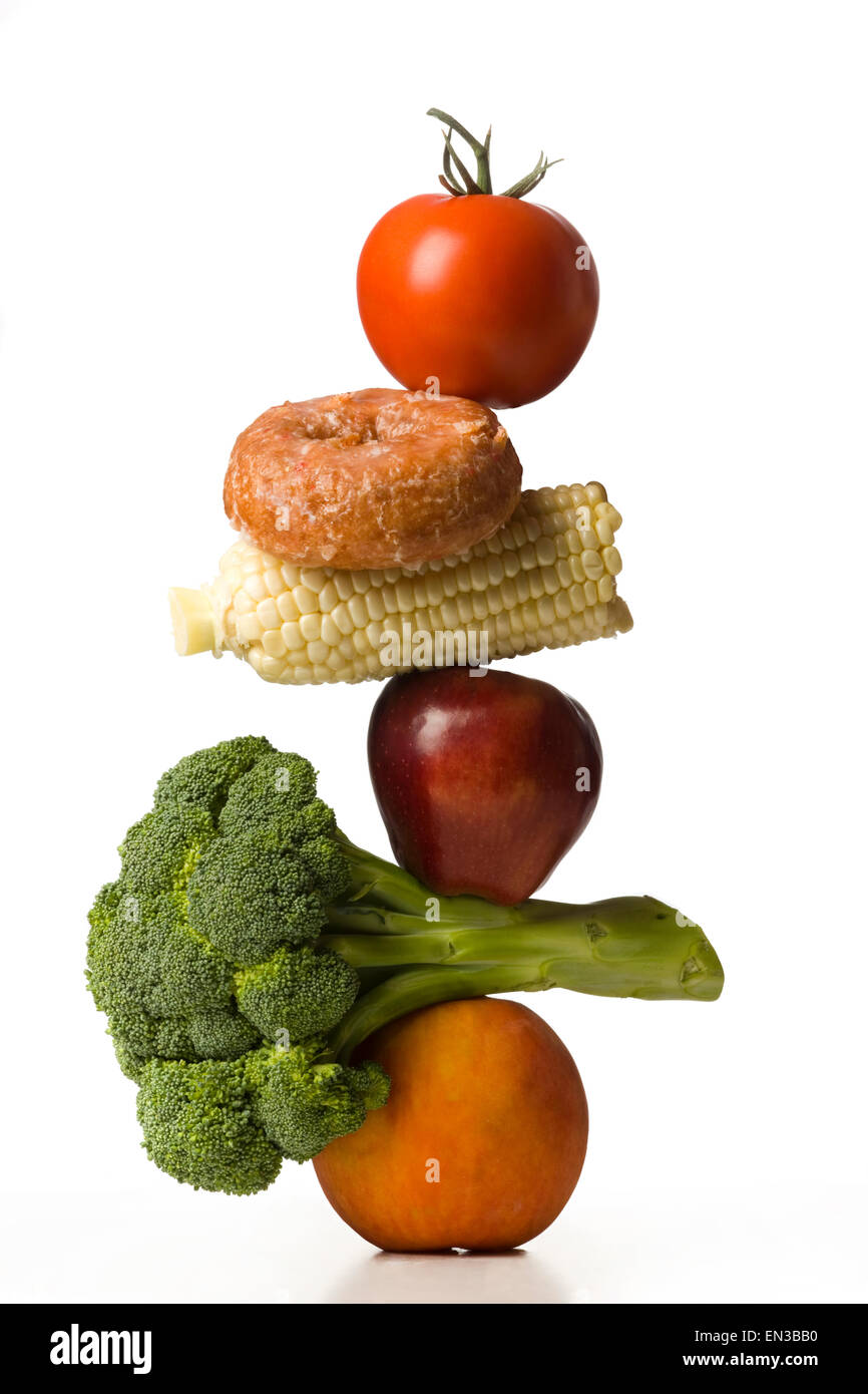 Pila di frutta e verdura con una ciambella in tra Foto Stock