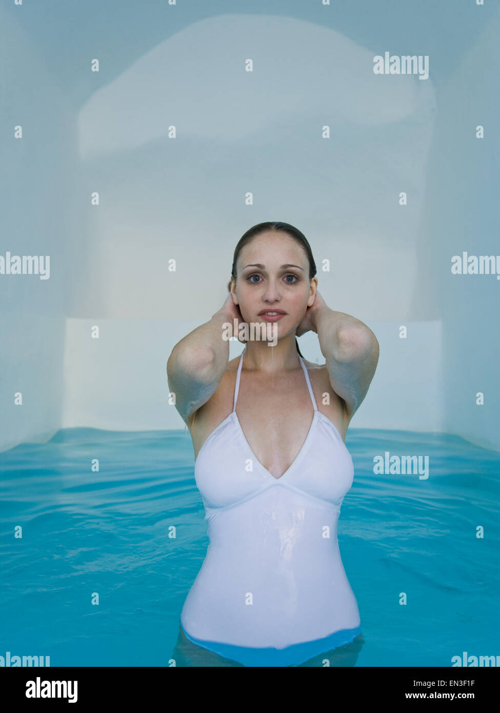 Donna in costume da bagno in piedi in piscina sorridente Foto Stock