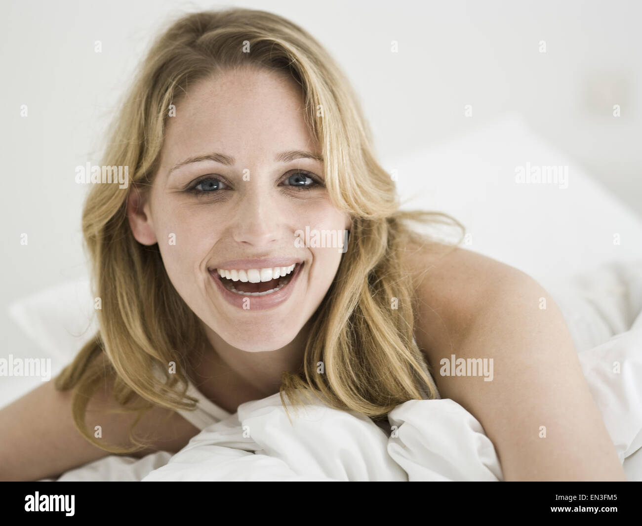 Primo piano della donna nel letto sorridente Foto Stock