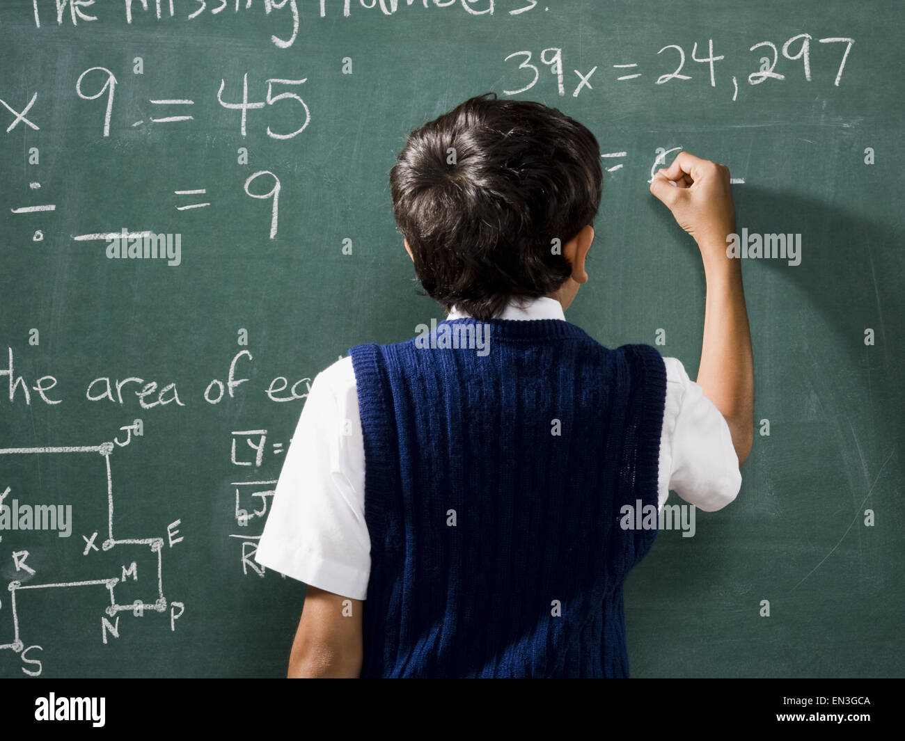 Vista posteriore del ragazzo in chalkboard facendo le formule matematiche Foto Stock