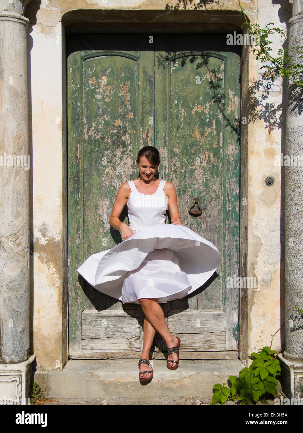L'Italia, Ravello, donna in piedi di fronte a annaffiato porta di legno, vento donna del vestito Foto Stock