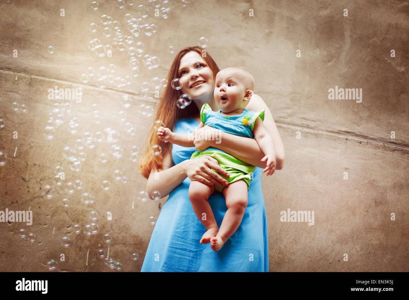 Giovane e bella madre con bambino soffiare bolle. La famiglia felice. Carino bambino sorpreso. Foto Stock