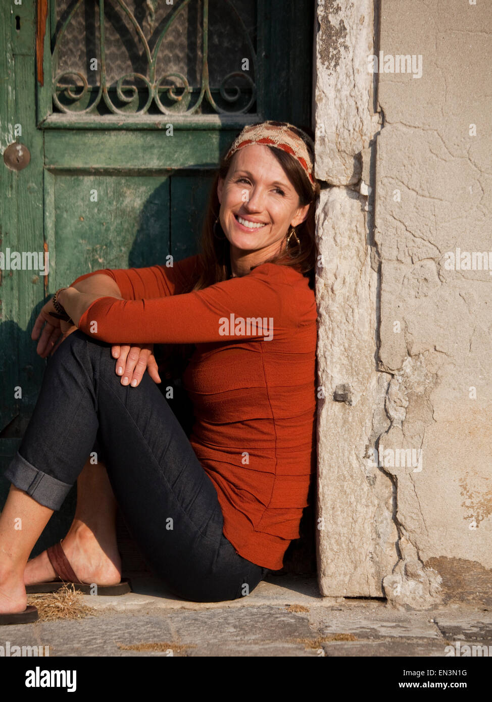 L'Italia, Venezia, Donna seduta dalla porta di legno nella città vecchia Foto Stock