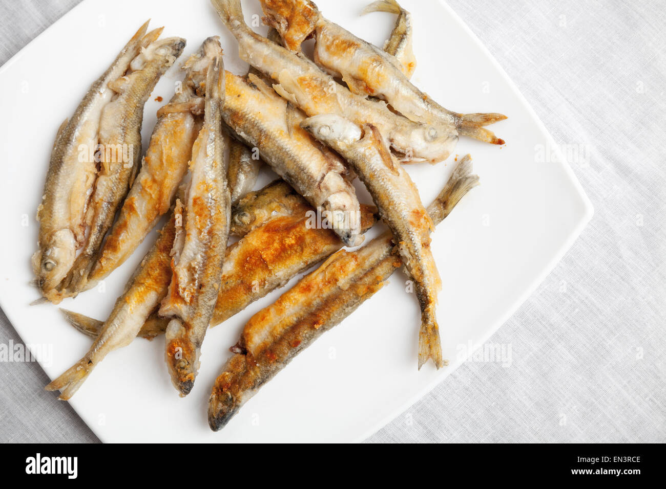 Pila di frittura di pesce smelleds giace su una piastra bianca, closeup foto con messa a fuoco selettiva, vista dall'alto Foto Stock