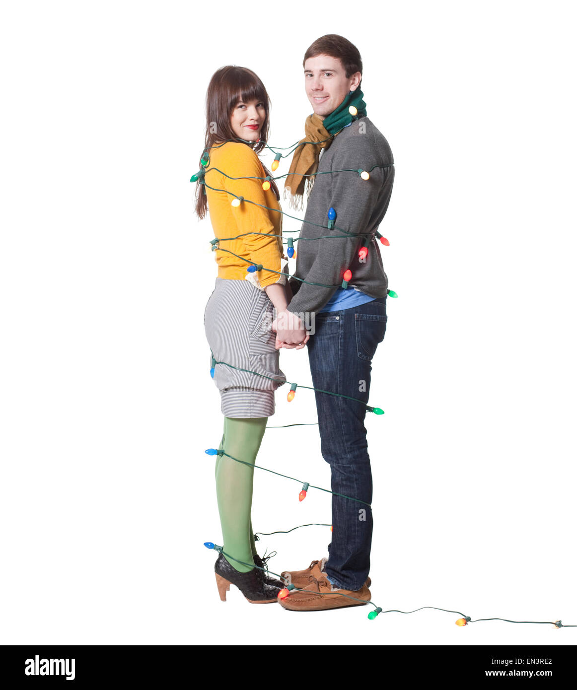 Studio shot di coppia giovane avvolto in luci di Natale Foto Stock