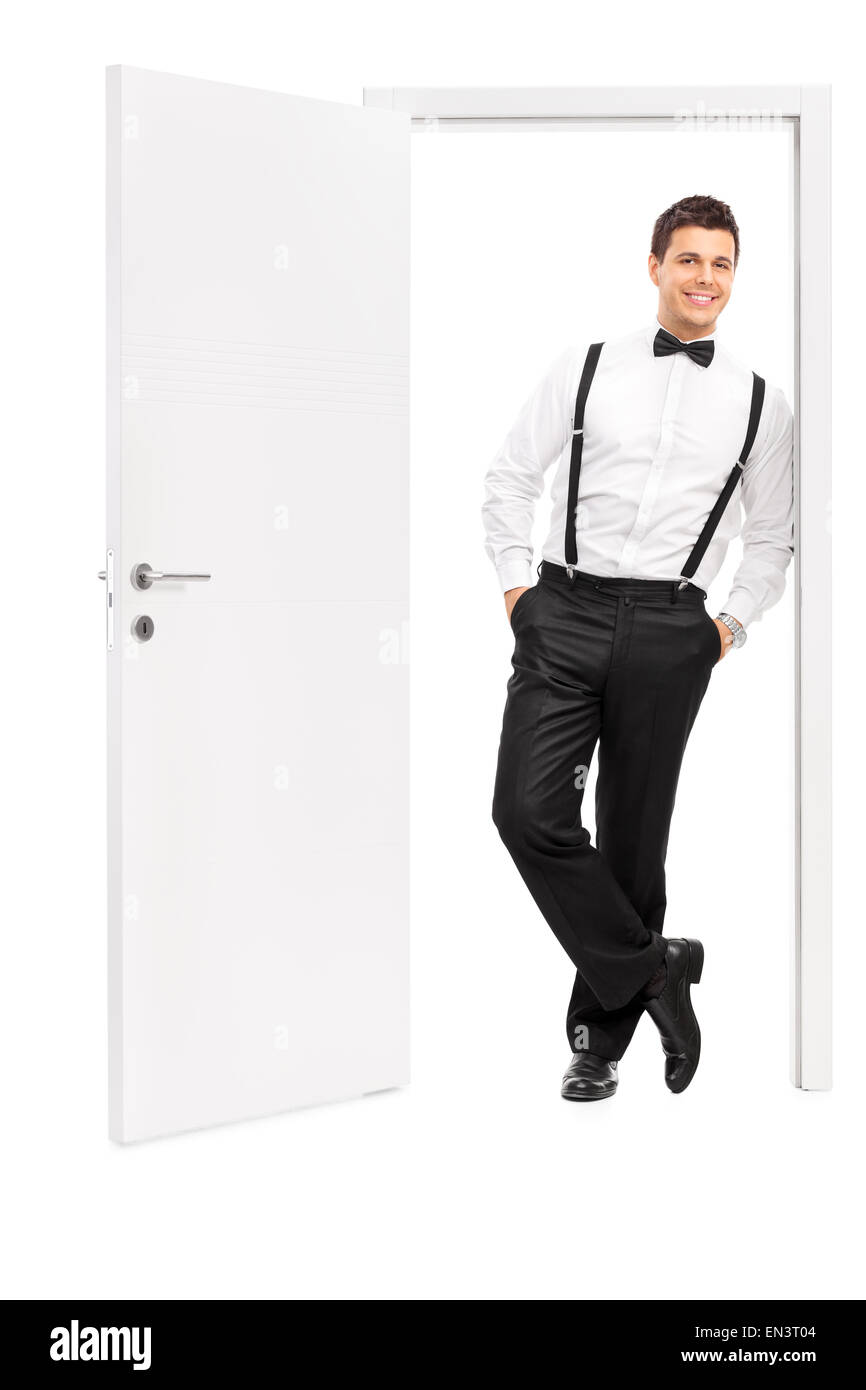 A piena lunghezza Ritratto di un bel giovane uomo in vestiti eleganti in posa da una porta aperta isolata su sfondo bianco Foto Stock