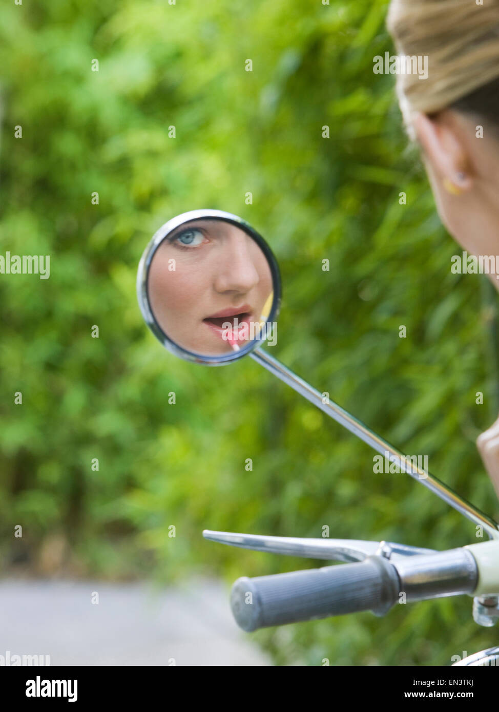Donna che guarda la telecamera nel suo specchietto retrovisore Foto Stock