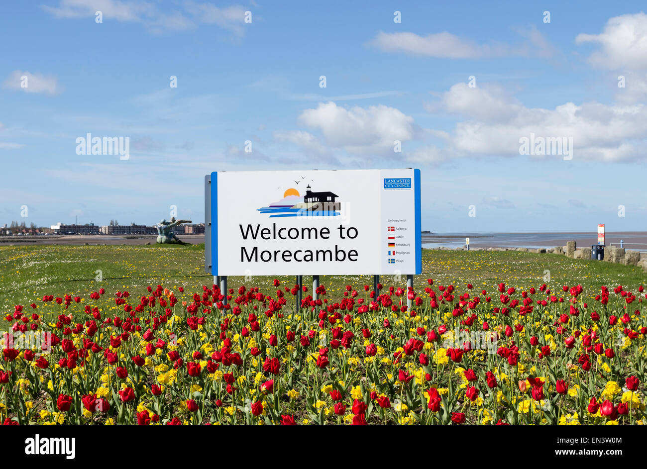 Rosso e tulipani gialli nella parte anteriore di un benvenuto a Morecambe segno su una soleggiata giornata di primavera Lancashire England Regno Unito Foto Stock
