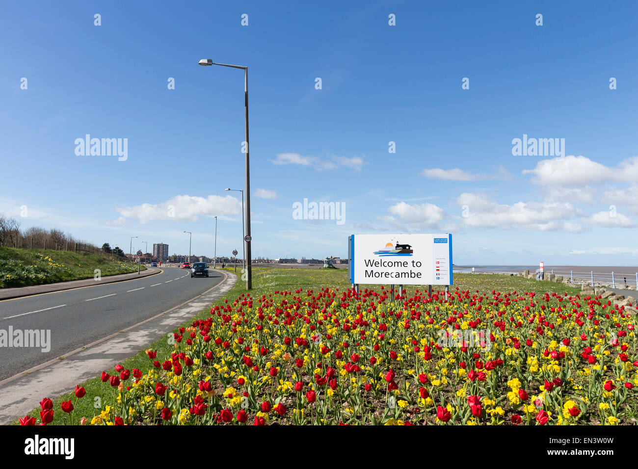 Rosso e tulipani gialli nella parte anteriore di un benvenuto a Morecambe segno su una soleggiata giornata di primavera Lancashire England Regno Unito Foto Stock